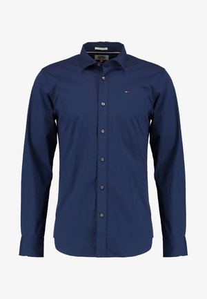 Chemise à manches longues bleu marine, boutonnée, en coton lisse. Dotée d'un col classique, d'une fermeture à boutons sur le devant et d'un petit logo sur la poitrine.