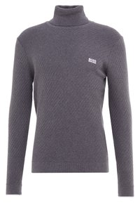 Pull à col roulé gris en tissu tricoté texturé, présentant un motif discret en chevrons et un petit logo brodé sur la poitrine.