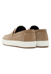 Zapatos de piel beige sin cordones con suela de goma blanca, que cuentan con costuras decorativas y una textura suave. Diseño minimalista con tacón redondeado.