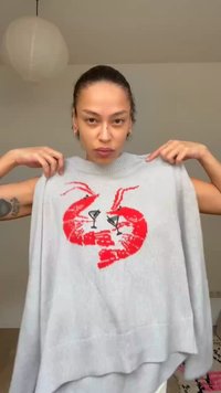 Άτομο που κρατά γκρι ανοιχτόχρωμο πουλόβερ με δύο κόκκινες γαρίδες και μαύρα ποτήρια κοκτέιλ τυπωμένα μπροστά.