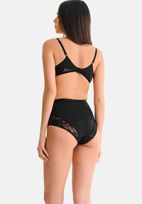 Ensemble de lingerie noire comprenant un soutien-gorge avec un dos en dentelle florale et des bretelles ajustables, associé à un slip taille haute avec des accents en dentelle.