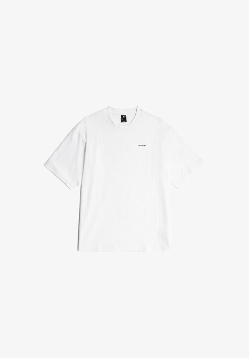 Camiseta de algodón blanca con mangas cortas y cuello redondo. Presenta un pequeño logo negro en la parte superior izquierda. Textura suave.