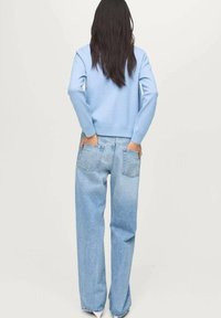 Ljusblå sweatshirt med ribbade ärmmuddar och nederkant, i kombination med ljusblå, löst sittande denimjeans med bakfickor och subtila sömmar.