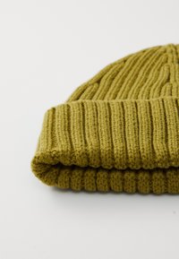 Oliven grøn strikket beanie med ribbet tekstur, der har en ombukket kant for ekstra varme og tætsiddende pasform.