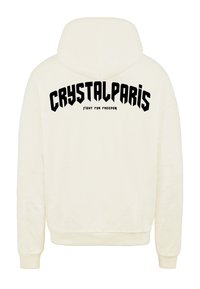 Krémová mikina s kapucí, na zadní straně s velkým černým grafickým textem "CRYSTALPARIS" a menším textem "BOJUJ ZA SVOBODU". Měkká látka, volný střih.