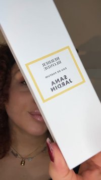 Białe prostokątne pudełko na perfumy ze złotymi akcentami, z czarnym napisem "Berber Blended", "Eau de Parfum" oraz "Sana Jardins".