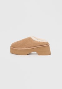Tan suede clog with a faux fur lining, round toe, and a chunky wooden platform sole. Soft texture and elevated design for comfort.