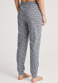 Zwart-witte bloemenprint pyjamabroek met een elastische tailleband, taps toelopende pijpen en ribgebreide manchetten. Zachte stof met een consistent patroon.
