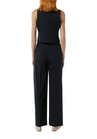 Marineblau gestreiftes Anzugset, bestehend aus einem ärmellosen Oberteil und einer weiten Hose. Der Stoff hat eine glatte Textur und einen dezenten Glanz.
