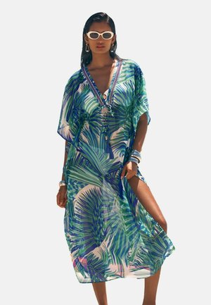 Sheer kaftan in green and blue tropical leaf pattern. V-neck with embellishments, short sleeves, and thigh-high side slit. Lightweight fabric.