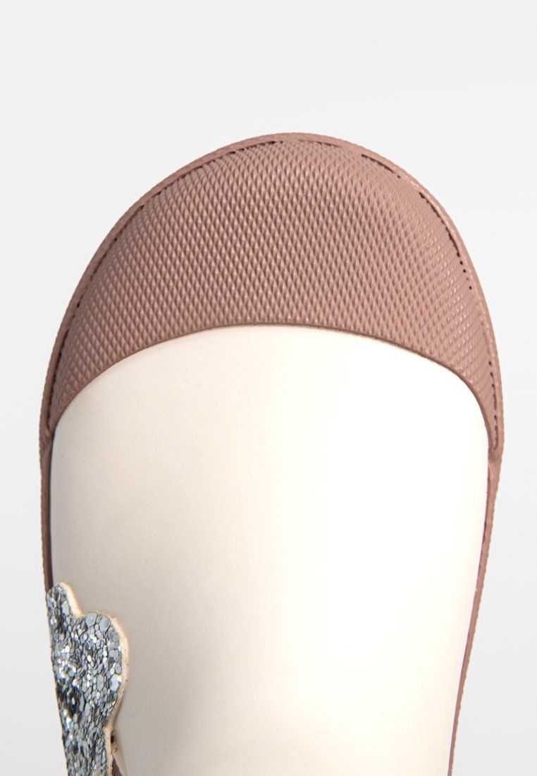Ballarina sintetica rosa con punta tonda, tomaia texturizzata e dettaglio metallico lateralmente, dotata di suola bianca liscia.