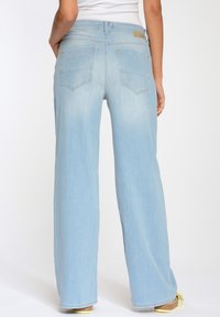 Světle modré široké džíny s vysokým pasem, které mají dvě zadní kapsy a vybledlý vzor. Tkanina má hladkou, denimovou strukturu.