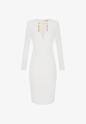 Vestido ajustado de manga larga blanco con escote en V profundo, adornos de cadena dorada y borlas en el cuello, con un dobladillo hasta la rodilla.