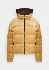 Fållig beige kordjacka med svart dragkedja, elastiska ärmmuddar, sidofickor, brun vadderad huva och vit The North Face-logotyp på bröstet.