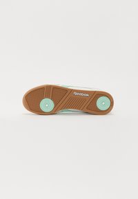 A Reebok sneaker talpa barna gumiból készült, textúrázott futófelülettel, mentazöld részletekkel és fehér színű, jól látható márkádlogóval rendelkezik.