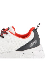 Αθλητικό παπούτσι από δίχτυ σε λευκό με κόκκινες λεπτομέρειες, μαύρο κάλυμμα στη φτέρνα, λευκή σόλα με στίγματα και αντιθετικό λογότυπο στο πλάι.