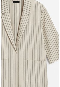 Blazer beige a righe con revers a notched, maniche corte e due tasche frontali. Realizzato in tessuto testurizzato con dettagli di cuciture diagonali.