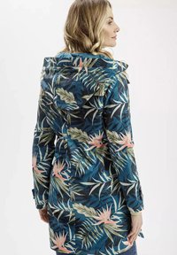 Kurtka przeciwdeszczowa we wzór kwiatowy w odcieniach niebieskiego, z zielonymi liśćmi i różowymi kwiatami. Wykonana z materiału wodoodpornego, z kapturem i dopasowanym w talii.