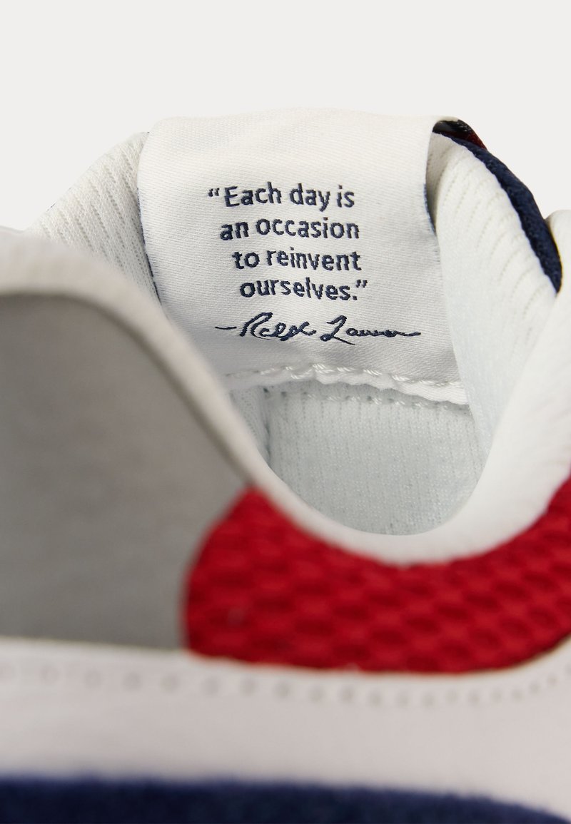 Intérieur d'une chaussure blanche montrant une étiquette en tissu avec la citation « Chaque jour est une occasion de nous réinventer. » signée Ralph Lauren.