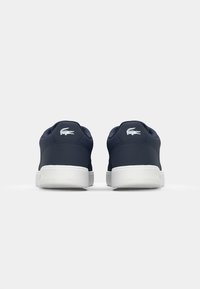 Marineblaue Sneakers mit einer glatten Textur, weißer Gummisohle und gesticktem Logo an der Ferse, die ein abgerundetes Design und einen gepolsterten Kragen aufweisen.