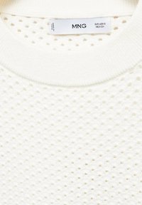 White knit sweater with a textured, perforated design. Features a round neck and ribbed edges, labeled with brand tag and sizing information.