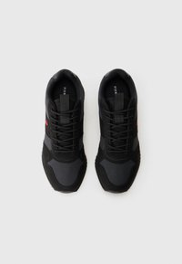 Pair of black sneakers with lace-up design, dark panels, and red logo detail, positioned side by side on a white background.
