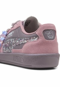 Sneaker rosa in suede con un lato grigio in materiale sintetico caratterizzato da un motivo a stelline, accenti decorativi pastello e un logo di personaggio sul tallone.
