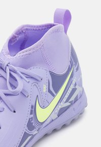 Zapatilla deportiva sintética morada con parte superior texturizada, swoosh de Nike en verde neón y detalles estampados en el costado.