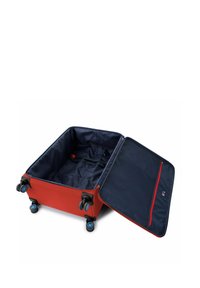 Roter Koffer mit hartem Schalenmaterial, vier blauen Rollen, offen mit einem marineblauen Innenraum, der ein Reißverschlussfach und Sicherungsriemen bietet.
