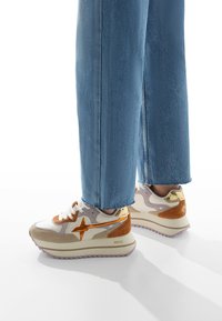 Le sneaker presentano un design bianco, beige e arancione, con una tomaia testurizzata e accenti metallici. La suola è spessa con un motivo di battistrada rosa.