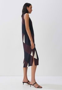 Ärmelloses Kleid in Marineblau und Burgunderrot mit cremefarbenen Akzenten. Merkmale sind geometrische Muster und seitliche Schlitze. Glattes Material und taillierte Passform.
