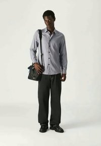 Ανοιχτό μπλε πουκάμισο με μακρύ μανίκι και κουμπιά, μαύρες παντελόνες με φαρδιά γραμμή, μαύρα παπούτσια και μια μαύρη τσάντα ώμου. Μονοχρωμία, casual σχέδιο.