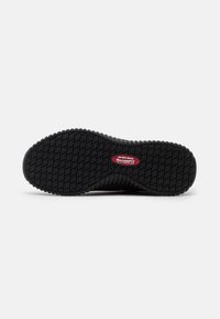 Black rubber shoe outsole with textured tread pattern; features Skechers branding in red. Designed for slip resistance.