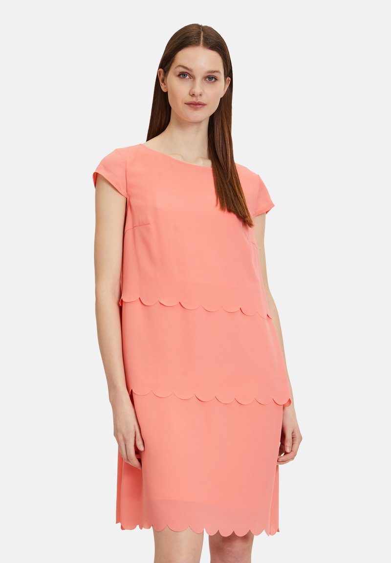 Korallenrosa Kleid aus glattem Stoff, mit einem gewellten Saum und kurzen Ärmeln. Gerader Schnitt, knielanges Design.