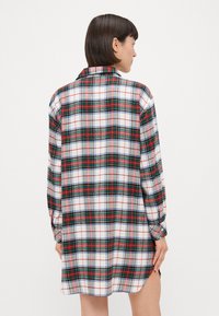 Camicia a quadri con un motivo a scacchi bianco, rosso e verde, maniche lunghe, colletto e spacchi laterali all'orlo per uno stile aggiuntivo.