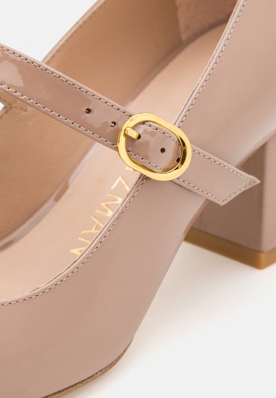 Escarpins Mary Jane en cuir synthétique rose clair avec une boucle dorée. Design à talon épais, texture lisse et bout rond.