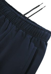 Marinblå sweatpants har ett elastiskt midjeband med dragsko, sidofickor och ett mjukt, texturerat tyg för komfort.