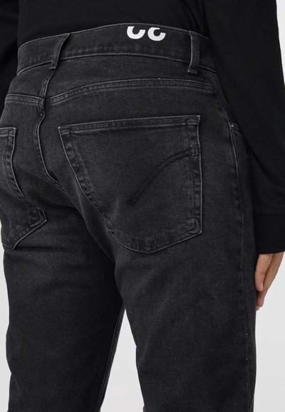 Jean en denim noir avec une légère texture délavée, présentant deux poches arrière et une taille marquée d'une marque blanche.