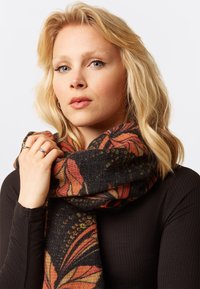 Knitted scarf with a black base featuring orange and red floral patterns. Soft texture, wrapped around the neck, with visible detail in design.