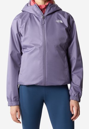 Vrouw draagt een paarse capuchonvest met rits en het logo van The North Face, marineblauwe legging en een roze top eronder.