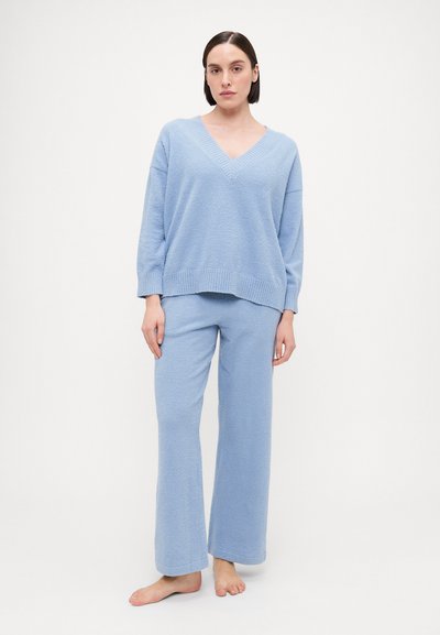 Light blue knit sweater with a V-neck and wide sleeves, paired with matching loose-fitting pants, both showcasing a soft texture.