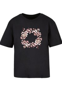 Black cotton t-shirt featuring a circular floral print in soft pink and white hues, with short sleeves and a crew neckline.