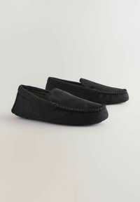 Sorte ruskinds mokkasinslippers med en syet detalje omkring tåen og et blødt interiørmønster. Flade gummisål for godt greb.