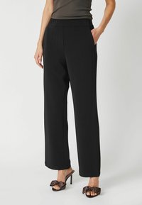 Black, high-waisted trousers made of soft fabric with a wide-leg design, featuring side pockets and a smooth texture.