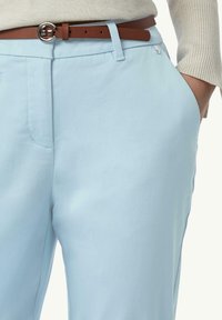 Lichtblauwe broek met een gladde structuur, voorzien van een bruine leren riem en een zilveren gesp. Zijklepzak zichtbaar, schoon, op maat gemaakt ontwerp.