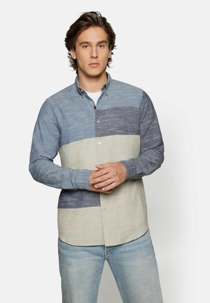Skjorte med knapper, der har vandrette striber i lyseblå, mørkeblå og beige. Lavet af tekstureret stof med klassisk krave og knaplukning.