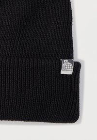 Fekete kötött sapka bordázott mintával és hajtókával. Címkéjén fehér teknős logó és a "Last Resort AB" felirat található.