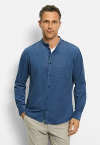Langärmliges Hemd mit Knopfleiste aus einem einfarbigen, tiefblauen Stoff, mit Stehkragen und einer Brusttasche. Glatte Textur und taillierte Passform.