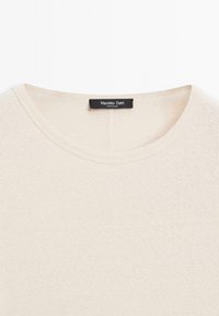 Maglione lavorato a maglia beige con scollatura rotonda,Texture morbida e un'etichetta con "Massimo Dutti" sul retro. Design semplice e minimale.