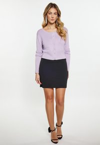 Cardigan lung cu mâneci lungi de culoare liliachiu, cu guler rotund și nasturi în față, combinat cu o fustă black tip creion și pantofi cu toc subțire negri.